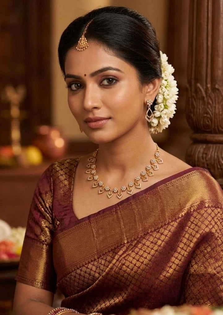 traditional south indian women wearing a, zircon diamond 18K gold-plated necklace and earring set showcasing delicate craftsmanship. The jewelry features sparkling diamond-like floral elements and curved drop shapes, making it a great choice to wear with sarees, lehengas, modern dresses, and festive wear for weddings, receptions, or family parties.