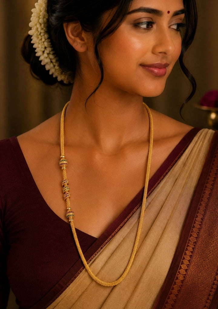 South Indian women wearing a  Elegant 18K gold plated South Indian thalli chain featuring a sleek woven design with decorative ruby and emerald bead accents for traditional wear.