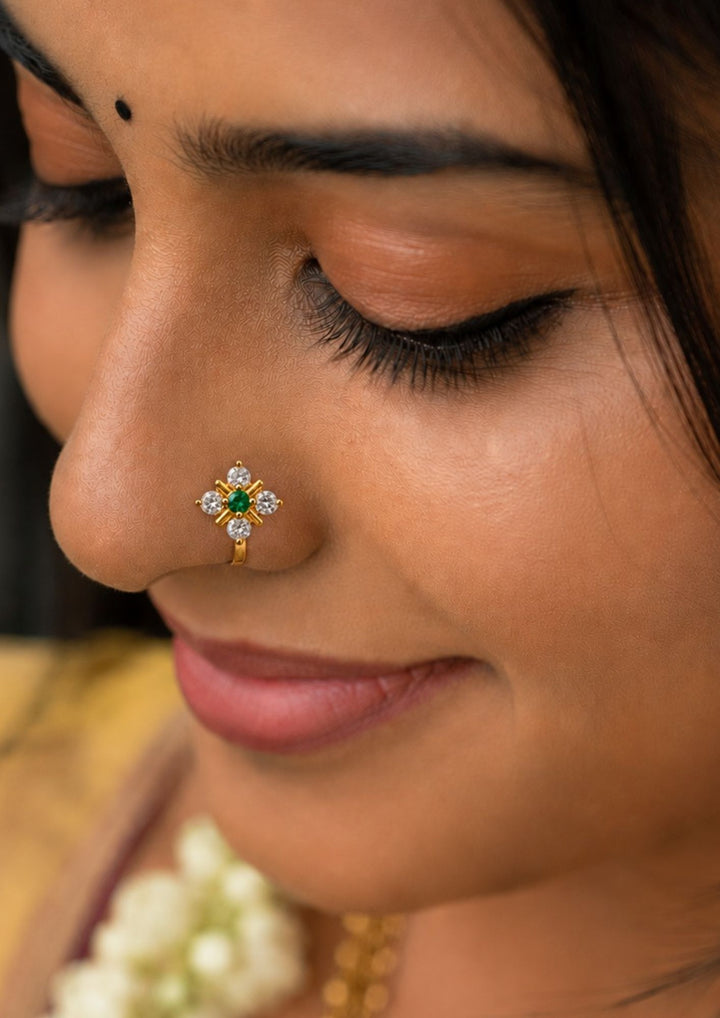 South Indian Women wearing Gold-plated nose pin design with leaf design using zircon diamonds and green gemstone with back open its perfect for weddings, dailywear and it is antifade color.