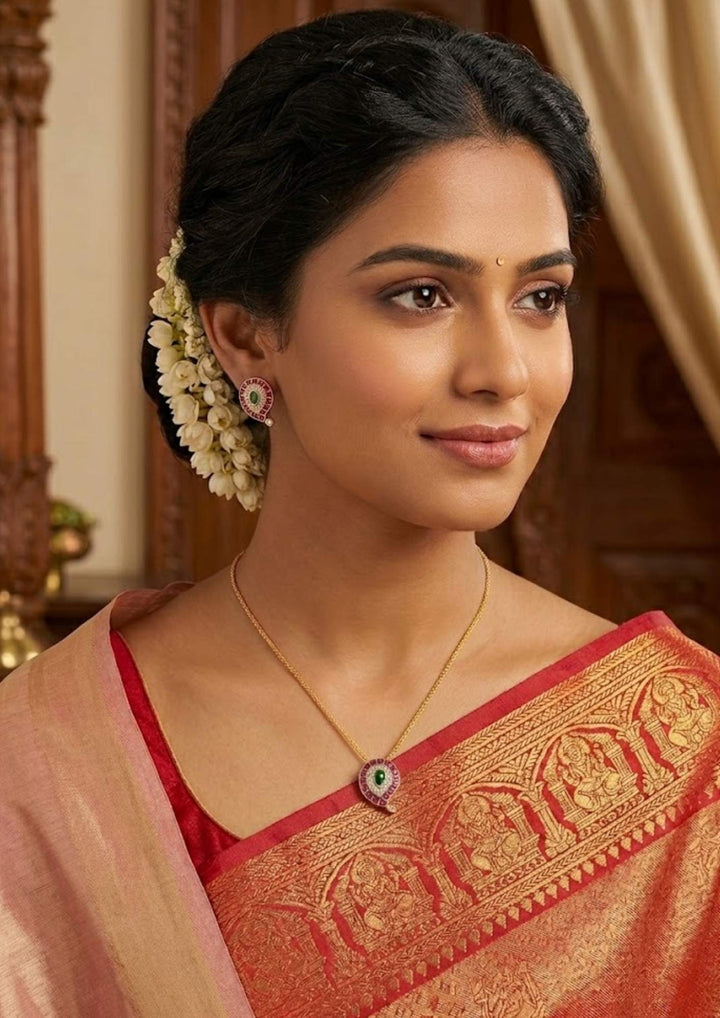 South Indian woman wearing Jadau Kundan Gold Plated mango pendant with matching earrings designed with pink stone border, green center kundan detailing, and shiny zircon work that gives a classy traditional jewelry appearance. The pendant features simple mango shape design while the earrings come with matching ethnic pattern finished in premium gold plating. This lightweight jewelry set offers sweat proof finish, anti-fade colour, skin-friendly, suitable for festivals, dailywear, weddings.