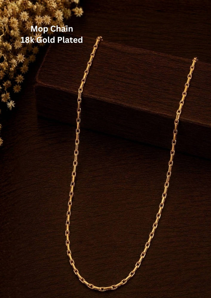 An elegant, sleek 18k gold-plated Mop chain displayed over a textured dark wooden surface. The chain features a continuous, sophisticated pattern of repeating cylindrical bar links seamlessly interconnected with small circular loops, offering a clean and polished modern look. Perfect for daily wear or for pairing with your favorite pendant.