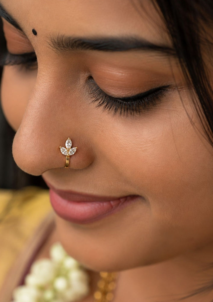 South Indian Women kepping a Gold-plated nose pin design with 3 leaf design using zircon diamonds with back open its perfect for weddings, dailywear and it is antifade color.