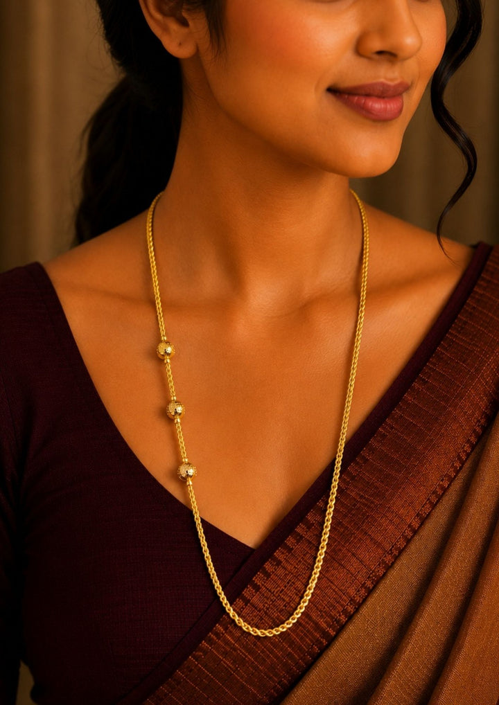 A close-up of a woman wearing a 18K gold plated thalli chain featuring diamond-cut textured gold bead accents with a premium twisted chain design for festive and traditional wear.
