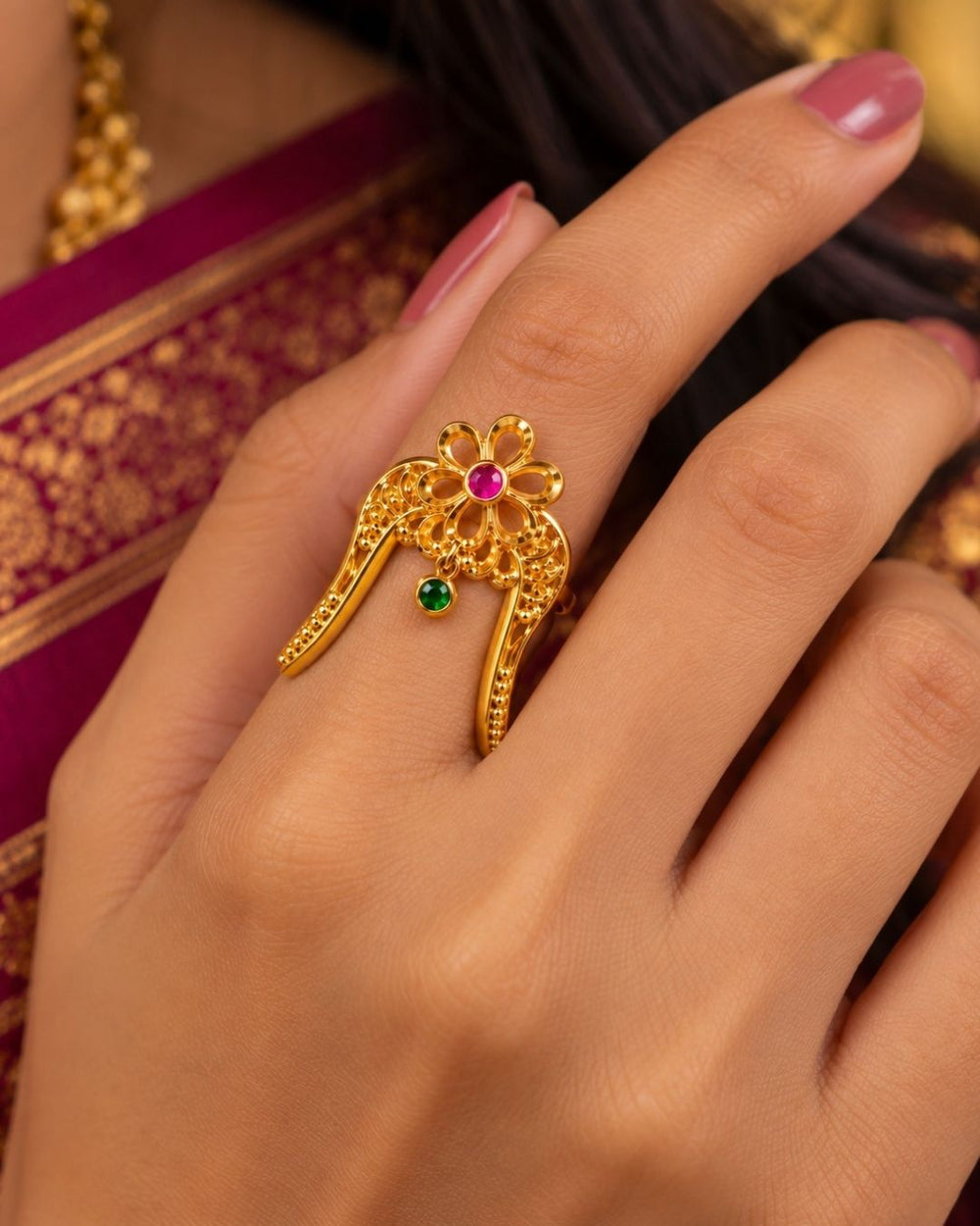 Traditional gold plated floral hair pin featuring an intricate openwork design, ruby and green stone embellishments, and curved prongs for securing the hairstyle.