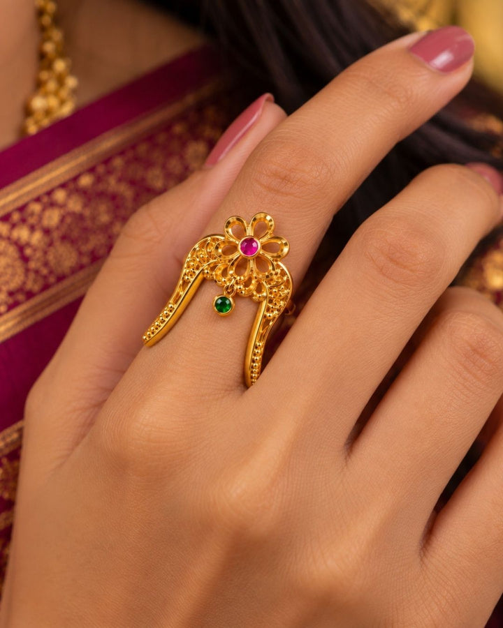 Traditional gold plated floral hair pin featuring an intricate openwork design, ruby and green stone embellishments, and curved prongs for securing the hairstyle.