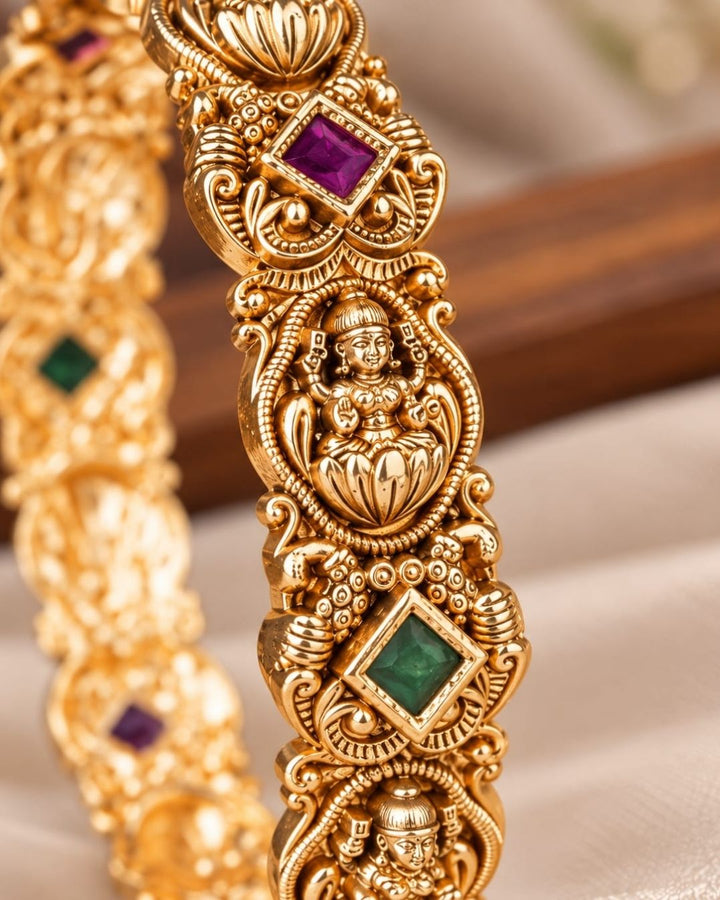 Traditional gold plated temple bangles with Goddess Lakshmi motifs, ruby pink and green square stones, and ornate antique-style craftsmanship.
