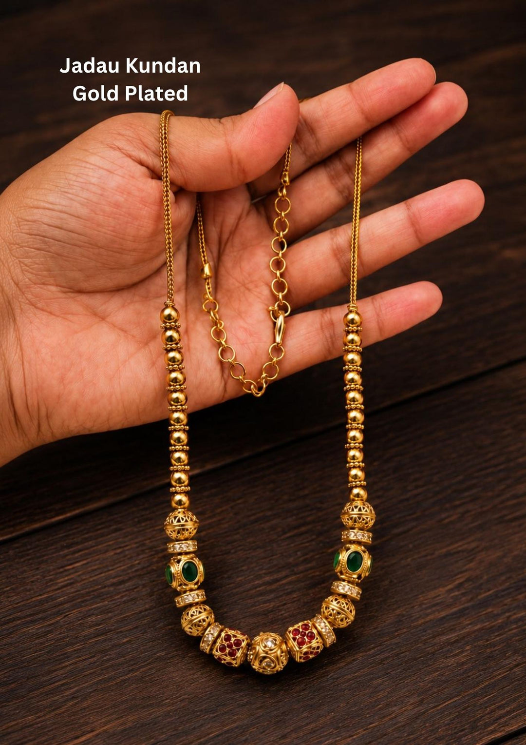 Antique Gold Plated Beads Mala with long traditional chain designed with gold beads , antique finish pattern, and South Indian jewelry style. The mala comes with kundans and green and red stones in cube pattern and balls pattern with green stones . this is sweat proof quality, anti-fade colour, skin-friendly finish, and is suitable for pooja functions, festivals, daily wear, and traditional occasions.
