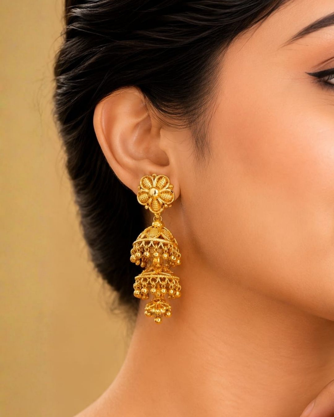 Beautiful traditional gold plated jhumka earrings featuring floral-inspired studs, intricate layered jhumka craftsmanship, decorative patterns, and elegant hanging gold bead accents. Perfect for sarees, festive occasions, weddings, and traditional events.