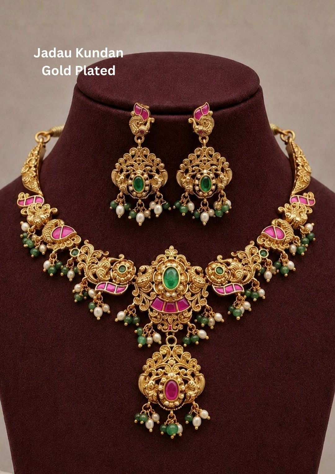 Traditional jadau kundan gold plated necklace set featuring intricate antique floral carvings with pink kundan accents, green center stones, pearl drops and green bead hangings. The heavy bridal necklace includes a grand pendant with matching chandbali style earrings, creating a rich South Indian traditional look suitable for weddings, bridal wear, temple functions and festive celebrations.