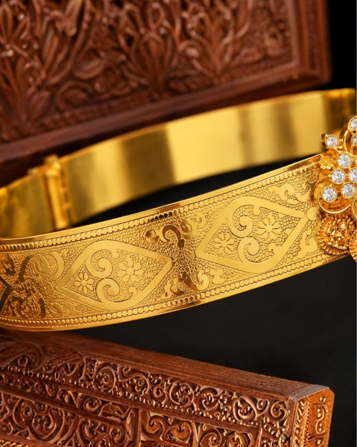 Elegant gold plated vaddanam with a floral crystal centerpiece and intricate detailing for festive and traditional wear.