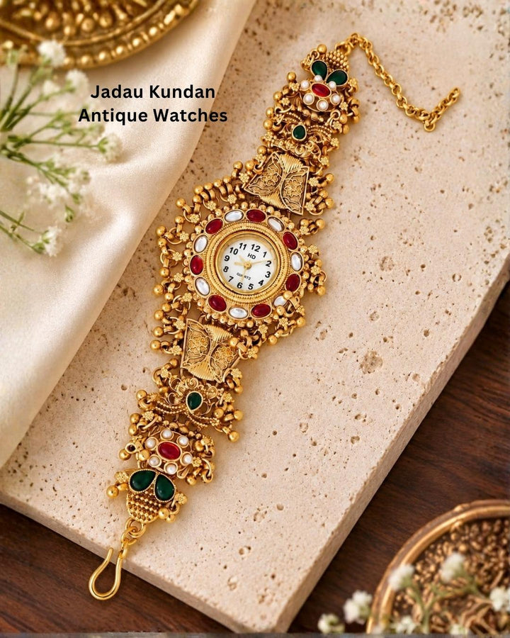 Traditional gold plated bracelet watch displayed diagonally on a beige stone surface with cream fabric and wooden accents.