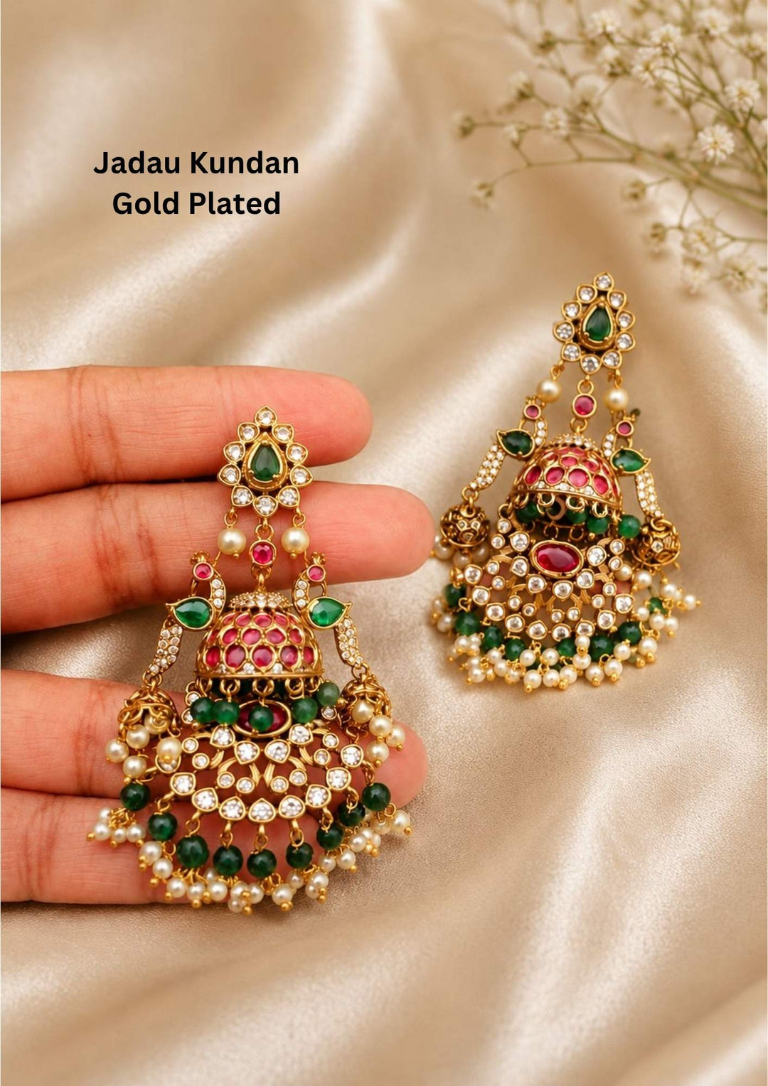 Jadau Kundan gold plated heavy bridal earrings.The design features a teardrop top stud with a green stone center, connecting to dual peacock motifs flanking a main dome-shaped jhumka. Below the dome is a wide, semi-circular crescent layout encrusted with white kundan stones, layered with hanging dark green beads and guttapusallu. perfect for weddingwear, festivals and it is anti fade color.