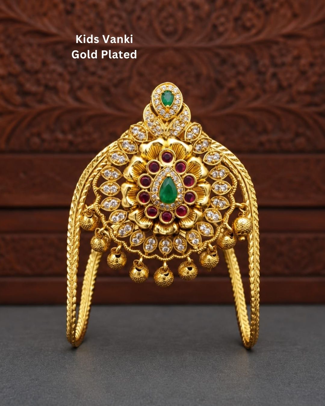 Premium gold plated baby vanki featuring an ornate floral motif with green and ruby-colored stone detailing, sparkling accents, and delicate hanging gold beads. Perfect for baby girls, traditional occasions, weddings, festivals, and gifting.