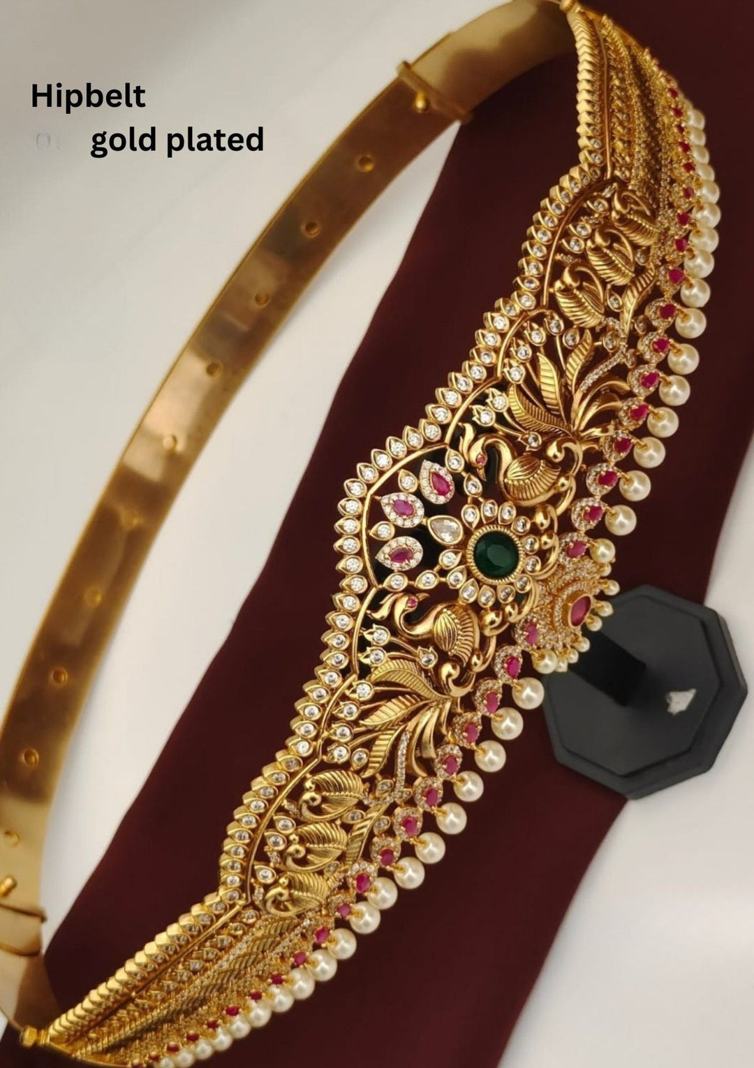 Gold-plated hip belt with intricate designs and gemstones on a white background