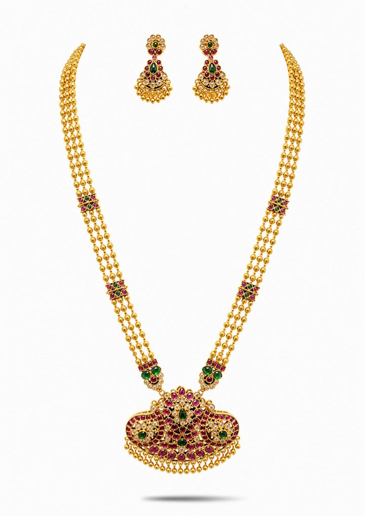 Gold necklace Set with a detailed pendant and earrings  on a white background with green and red stones come with jadau kundan in necklace set with beads and in pendent shows clear design and in detailed shown in picture it will not fade color and water proof can used for festivals, bridals, and weeding's  