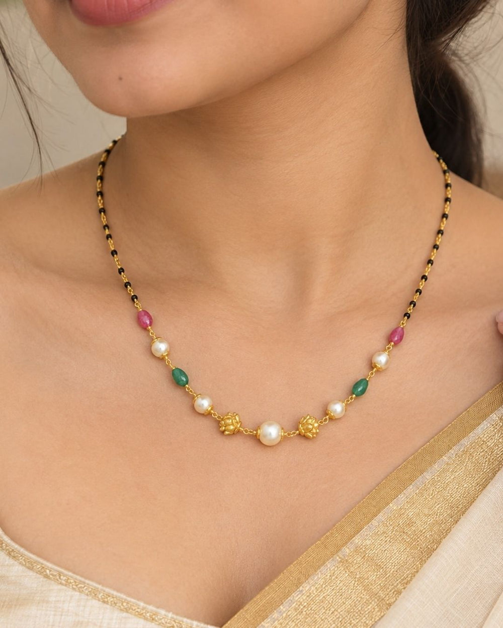 Traditional gold plated necklace featuring black beads, white pearls, green and pink stone accents, and decorative gold elements, perfect for ethnic and festive wear.