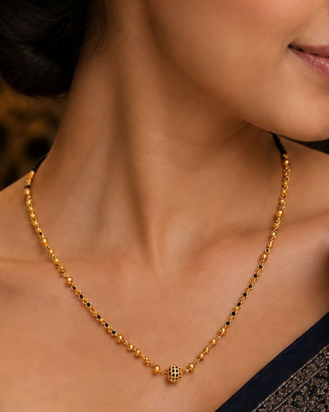 Gold replica black beads necklace featuring a delicate single-strand design, small gold-toned beads, and a decorative round center pendant, displayed on a maroon jewellery bust.