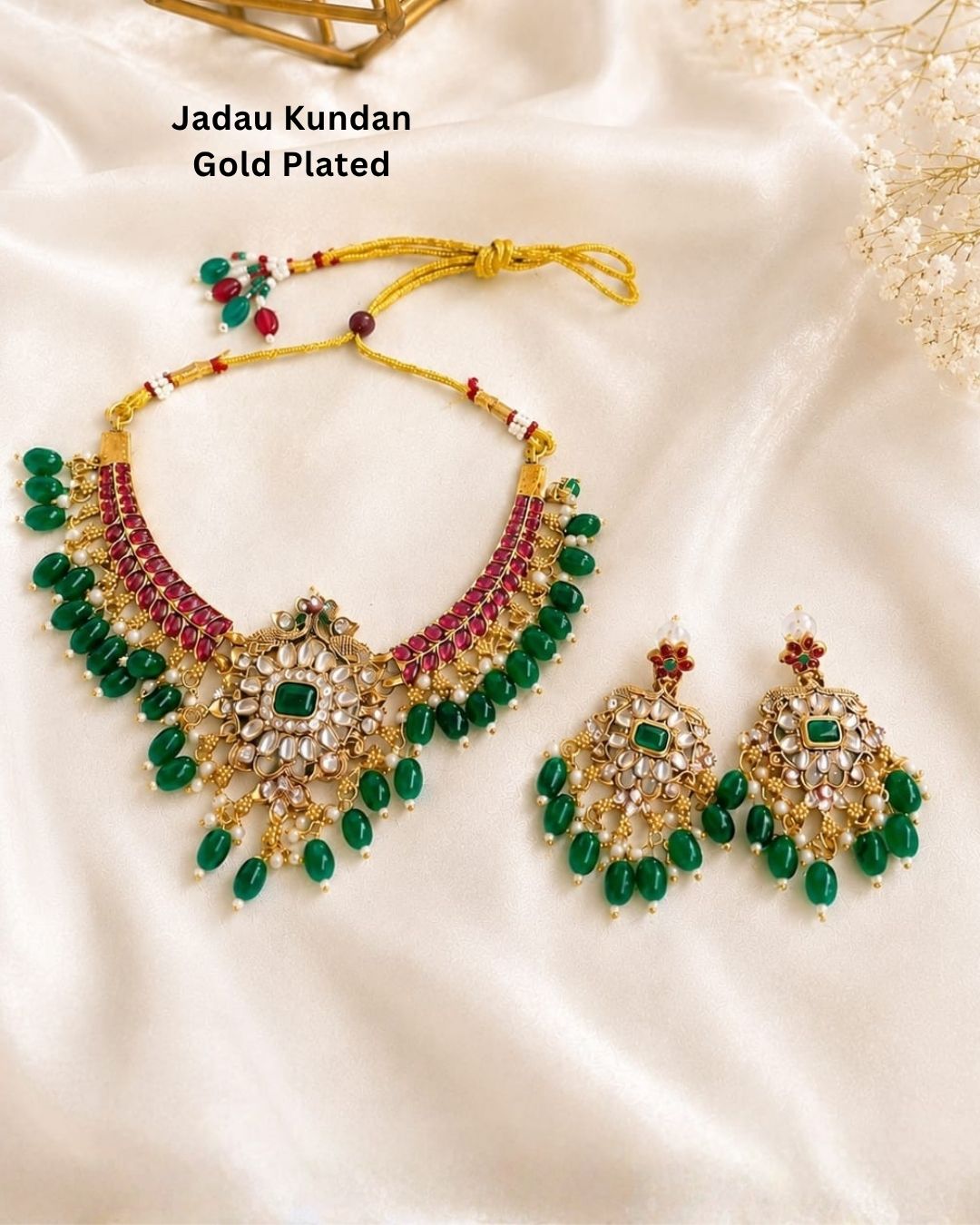 Elegant gold plated Kundan necklace and earrings set adorned with green oval beads, ruby stones, pearl embellishments, and a floral pendant design for festive and bridal wear.