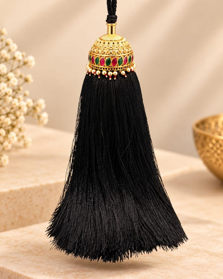 Elegant gold plated Jada Gantalu with an ornate dome-shaped design, green and pink stones, pearl and bead accents, and long black tassels, perfect for bridal and festive hairstyles.