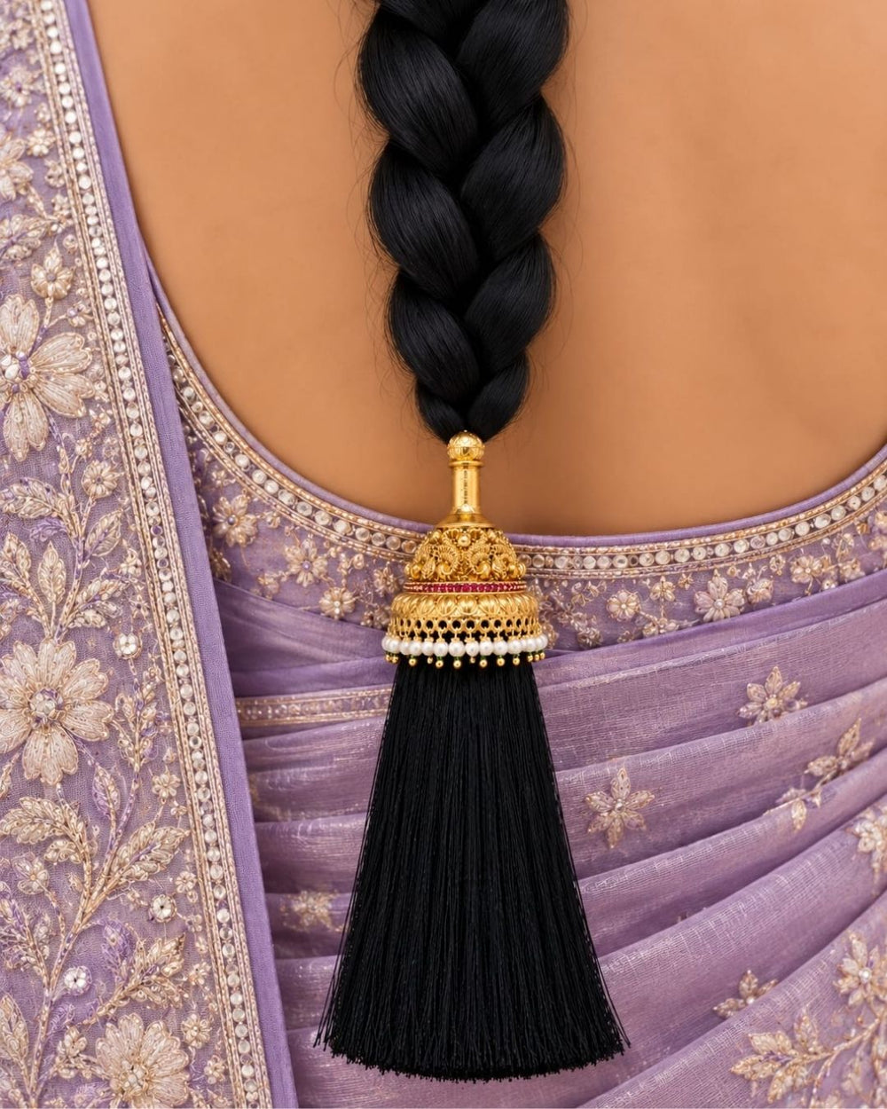 Elegant gold plated Jada Gantalu with intricate temple-inspired craftsmanship, ruby stone accents, pearl detailing, and long black tassels, perfect for bridal and festive hairstyles.