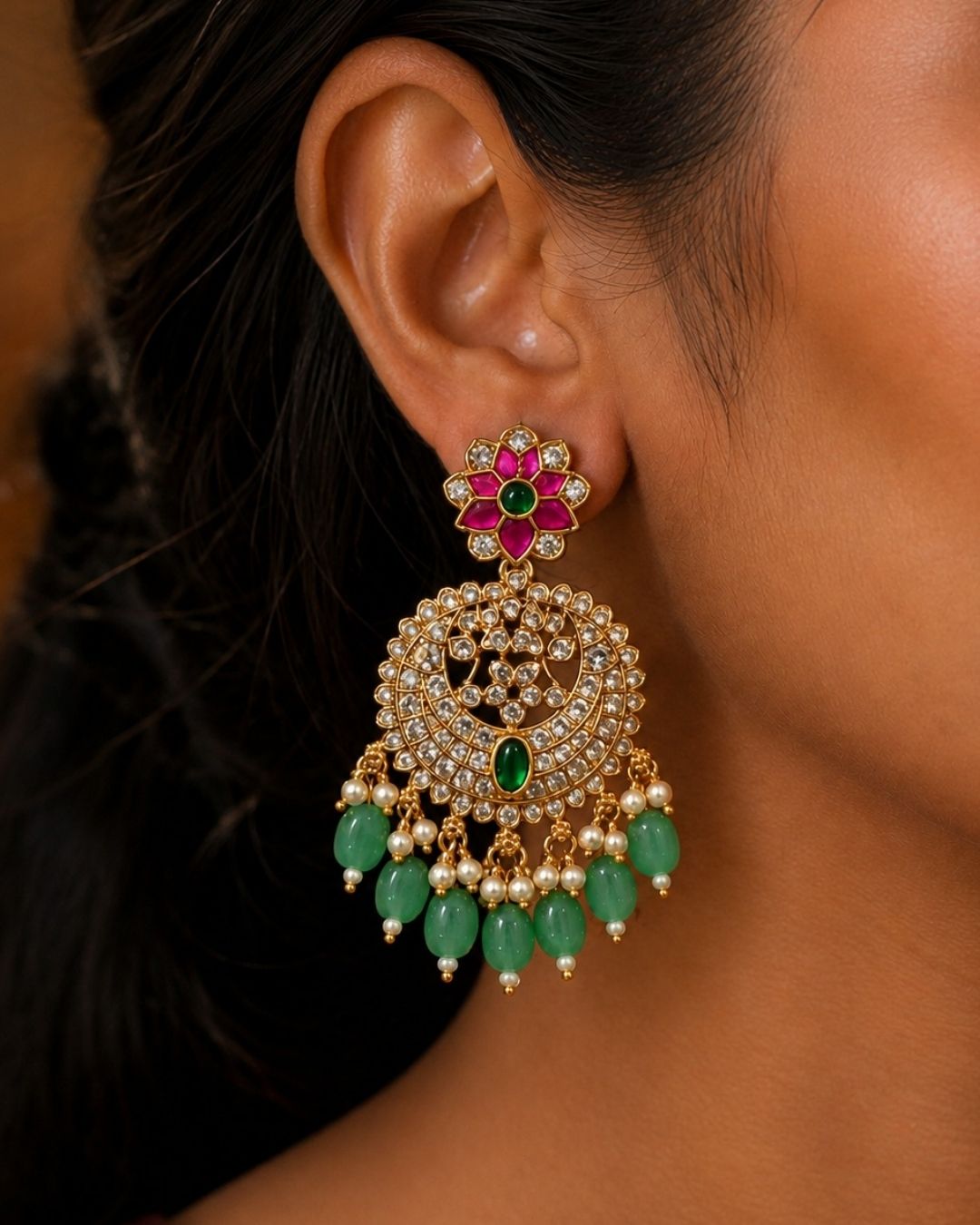 Beautiful Jadau Kundan gold plated Chandbali earrings featuring ruby pink floral motifs, sparkling white kundan stones, green stone accents, pearl detailing, and green bead drops. Perfect for weddings, festivals, temple visits, traditional outfits, bridal wear, and premium gifting.