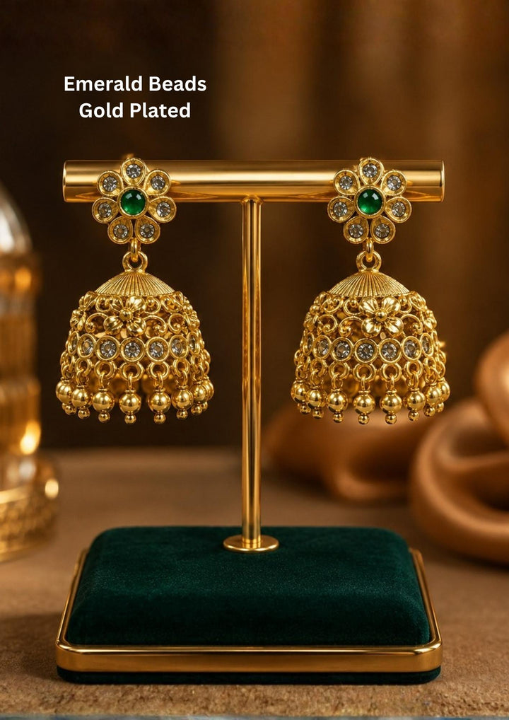 Elegant emerald beads gold plated jhumka earrings featuring floral stud tops adorned with sparkling white stones and green center beads. The dome-shaped jhumkas showcase intricate antique detailing with hanging gold bead danglers, creating a timeless traditional look.