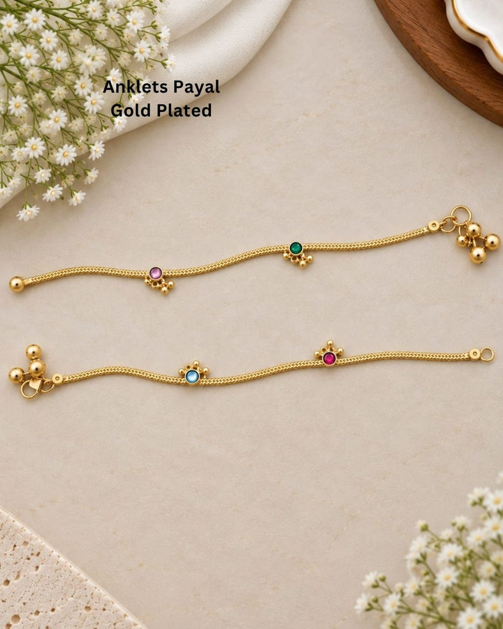 Beautiful gold plated payals featuring delicate chain patterns with pink, green, and blue stone embellishments and charming hanging bead details. Perfect for traditional wear, festive occasions, weddings, daily wear, and gifting.