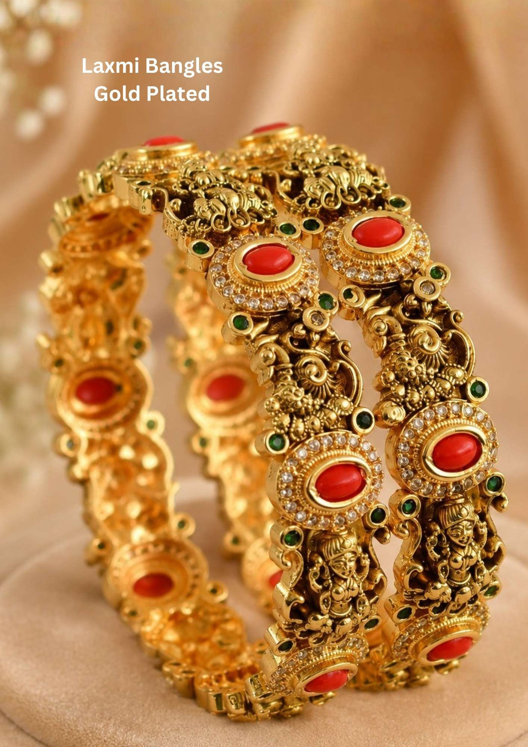 Gold-plated Laxmi Bangles with red and green stones. temple design gold plated bangles featuring oval coral red stones surrounded by sparkling white zircon accents. The bangles showcase intricate deity motifs, antique craftsmanship, and green stone embellishments, creating a luxurious traditional South Indian jewelry look. ideal for weddings, festivals, and bridal wear.