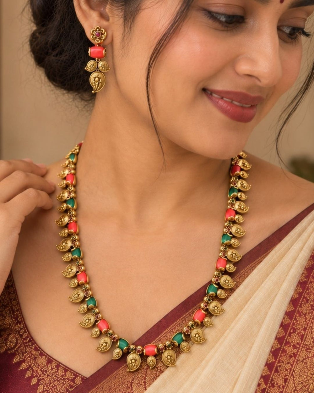 Elegant gold plated coral temple jewellery set featuring detailed traditional motifs, coral-colored and green stone embellishments, and matching earrings, perfect for festive and ethnic wear.