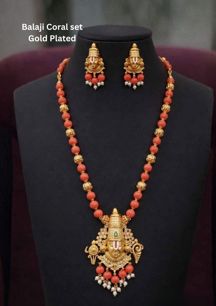 Gold Plated Balaji Coral set featuring a long bead necklace with a detailed Lord Venkateswara pendant and matching stud earrings. The set combines vibrant orange coral beads, textured gold spacer beads, a green crown stone, and completed with white pearl guttapusalu. Perfect for traditional wear, festivals, lightweight comfort, sweat proof quality, anti-fade colour, skin-friendly finish, and is suitable for weddings, pooja functions, 