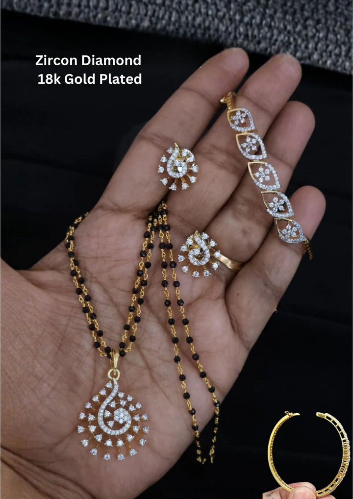 gold plated bridal mangalsutra combo set. The main double-strand black bead necklace features an openwork swirling teardrop pendant densely paved with pure Zirconian diamonds. The matching set includes a pair of teardrop earrings, a coordinate statement ring, an adjustable sliding leaf bracelet, and a rigid round bangle.