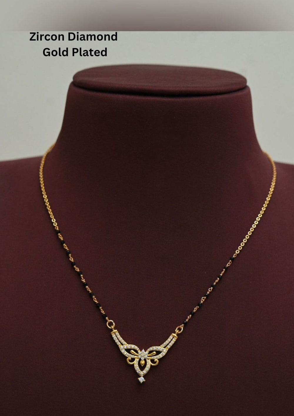 Modern Zircon Diamond gold plated mangalsutra necklace The design features a delicate gold link chain transitioning into sections of traditional small black beads on both sides. The central pendant showcases a sleek, contemporary curved V-shape and a stylized butterfly or floral motif encrusted with sparkling white cubic zirconia stones. This elegant neckpiece perfect for daily wear, office wear, and casual outfits.