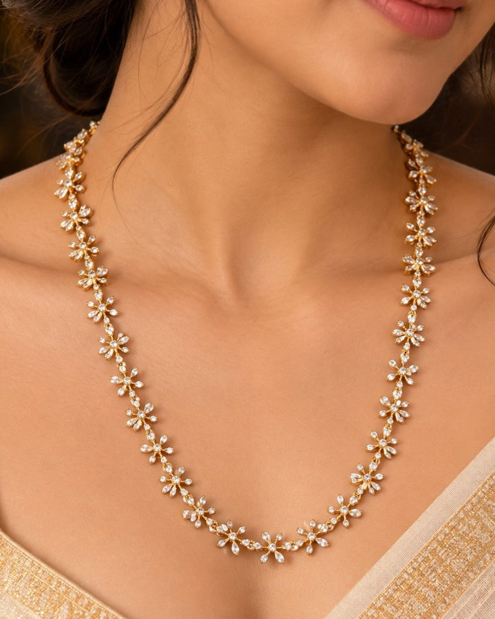 South Indian women wearing  Pure Zirconian Diamond Gold Plated long chain necklace and matching stud earrings set. The jewelry designed with floral pattern made of sparkling cube zirconia stones on a gold-plated base for festivals, temple visits, weddings, functions and dailywear