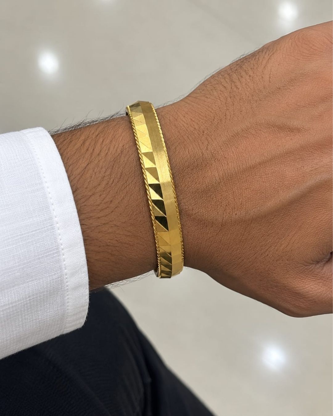 Elegant gold plated men’s kada featuring a broad geometric patterned band with polished finish and twisted border detailing, perfect for traditional and modern wear.