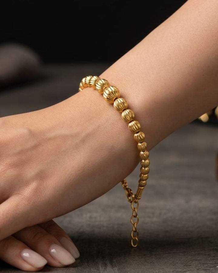 Beautiful gold plated beaded bracelet featuring a sequence of intricately textured round beads, delicate chain detailing, and a polished finish. Perfect for everyday wear, festive occasions, traditional outfits, parties, and gifting.
