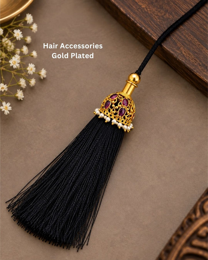 Traditional gold plated hair accessory featuring an ornate dome-shaped design with ruby-colored stones, pearl detailing, a long black tassel, and a decorative black cord, perfect for festive and traditional hairstyles.