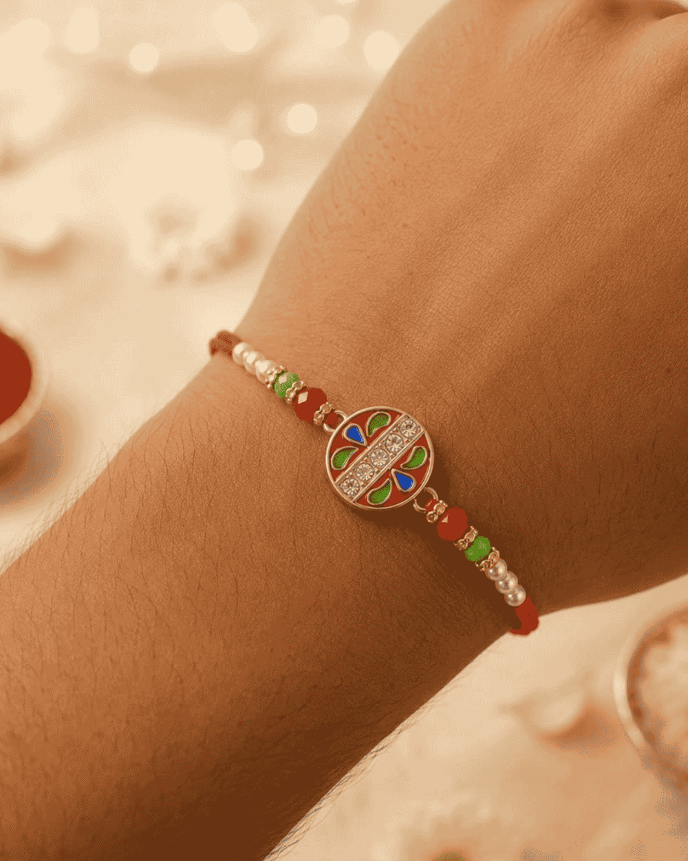 Elegant Floral Chakra Rakhi showcasing a decorative circular centerpiece with colorful enamel detailing, crystal embellishments, pearl beads, and an adjustable bracelet.