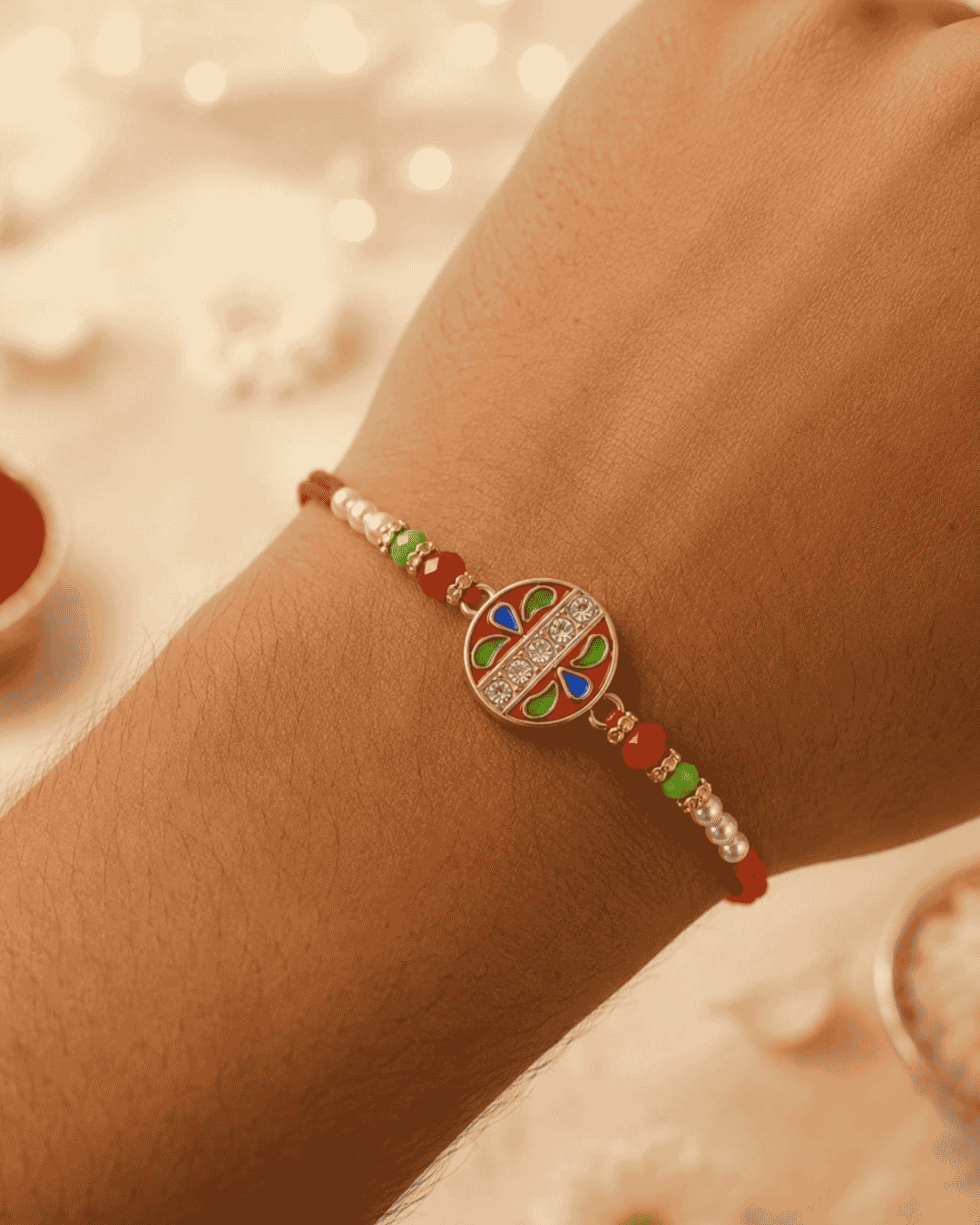 Elegant Floral Chakra Rakhi showcasing a decorative circular centerpiece with colorful enamel detailing, crystal embellishments, pearl beads, and an adjustable bracelet.