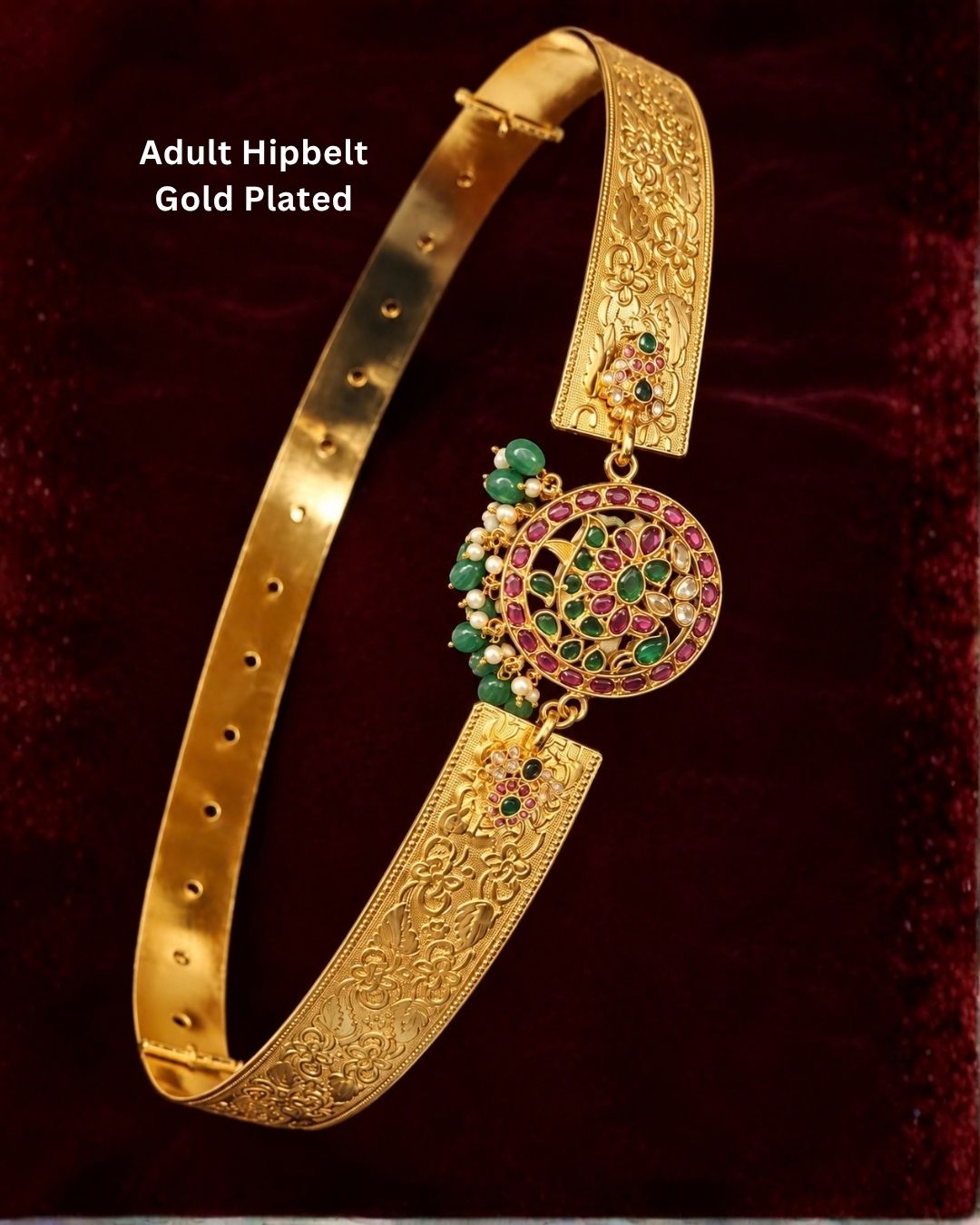 Traditional gold plated hip belt featuring detailed floral craftsmanship, a large circular multicolor stone centerpiece, green and ruby stones, pearl embellishments, and adjustable fastening, perfect for bridal, festive, and traditional wear.