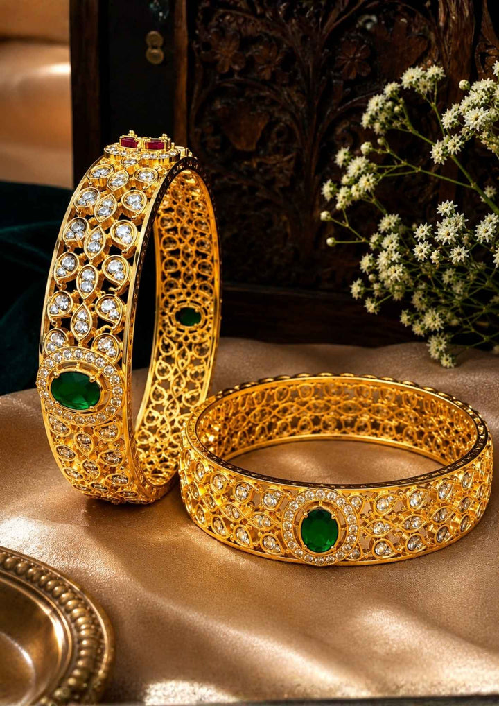 Beautiful Jadau Kundan gold plated openwork bangle pair featuring dazzling white kundan stones, emerald green center stones, and intricate traditional craftsmanship. Perfect for weddings, festivals, temple visits, traditional outfits, family functions, and premium gifting.