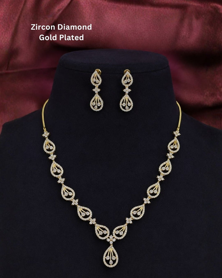 Designer gold plated CZ necklace set with shimmering teardrop patterns, floral connectors, and matching drop earrings, perfect for festive and party wear.