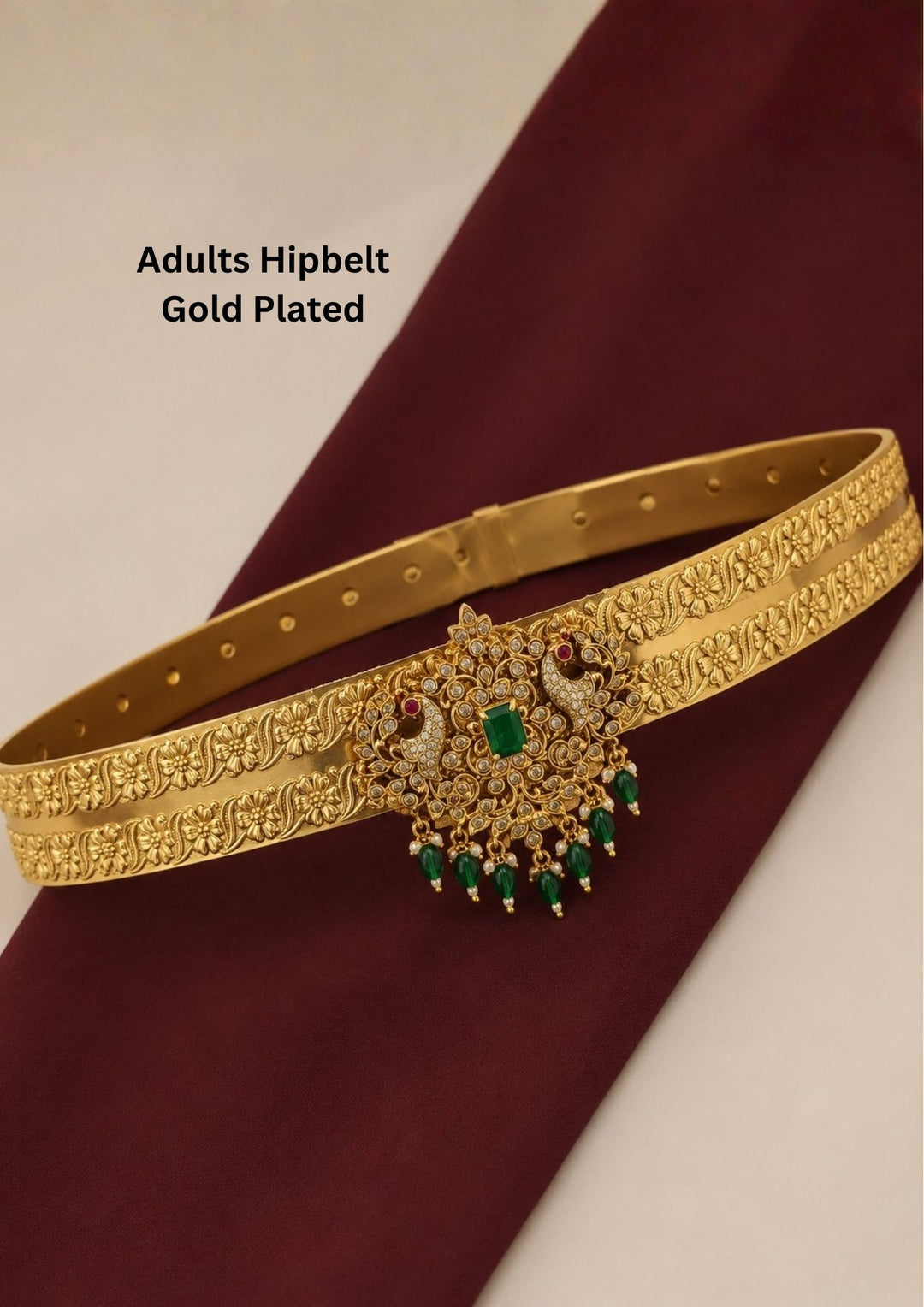 Elegant gold plated traditional hipbelt featuring floral engraved patterns with a grand peacock-inspired centerpiece embellished with sparkling zircon stones, an emerald green center stone and green bead danglers.