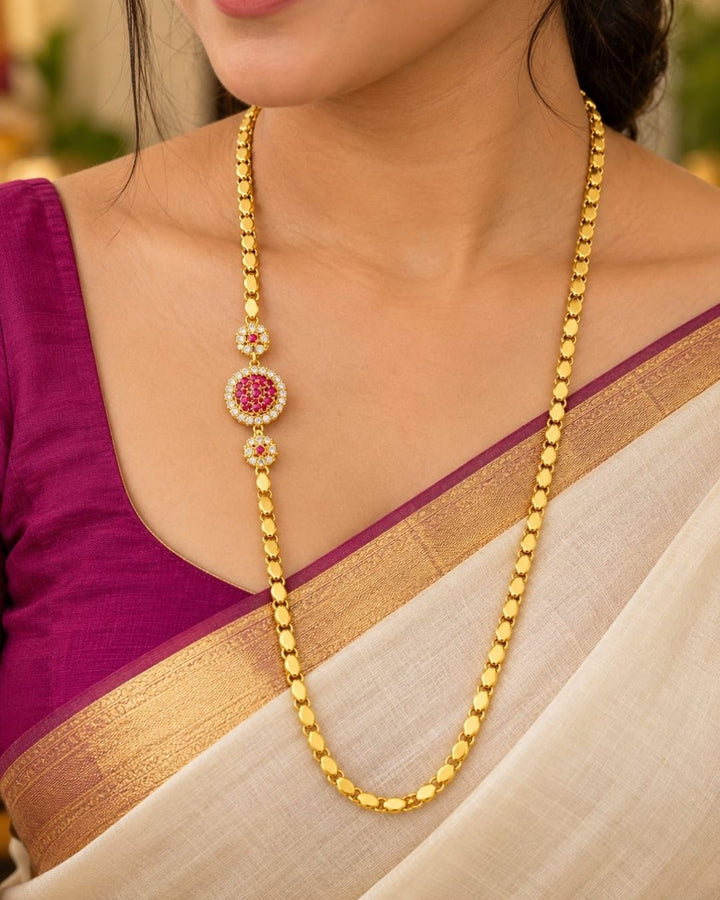 Designer gold plated thalli chain displayed on beige silk with a carved wooden jewellery box, featuring a round ruby stone centre design and matching ornamental accents.