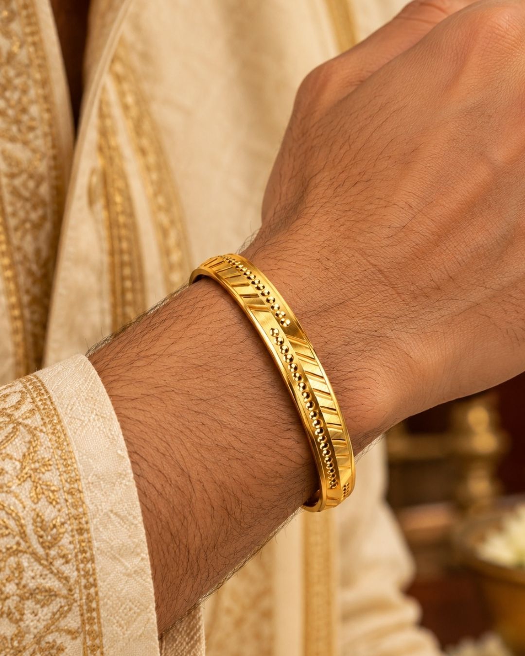 Gold plated men’s kada displayed upright on a dark textured surface, highlighting its geometric detailing and glossy finish.