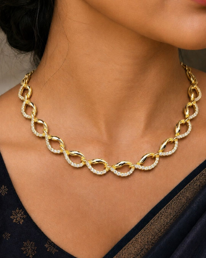 South Indian women Beautiful gold plated loop necklace set featuring interlinked curved motifs accented with sparkling clear stones and matching elegant drop earrings. Perfect for daily wear, festive occasions, parties, traditional outfits, and premium gifting.