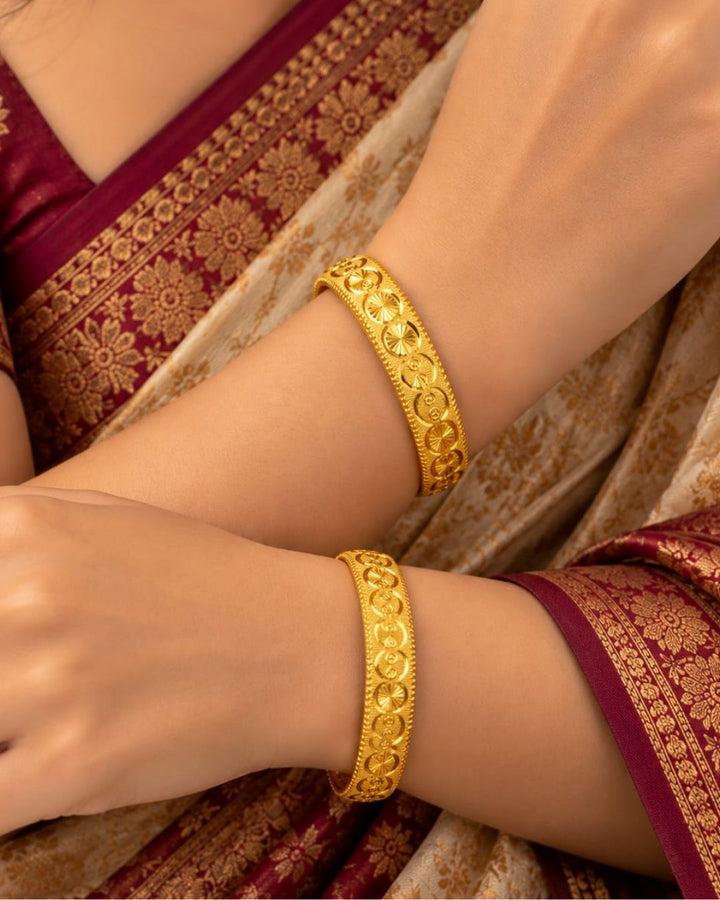 Traditional gold plated designer bangles featuring repeating floral and circular motifs with intricate textured borders, perfect for festive, wedding, and traditional occasions.