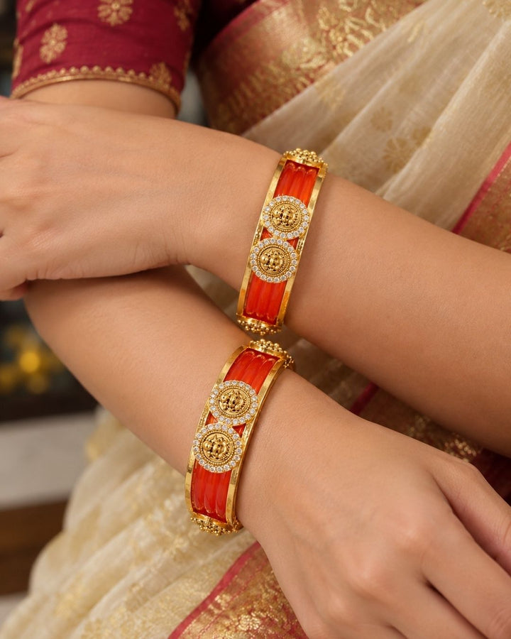 Traditional gold plated interchangeable bangles featuring rich red detailing, polished gold borders, circular motifs embellished with sparkling white stones, and decorative bead accents, perfect for festive, wedding, and traditional occasions.