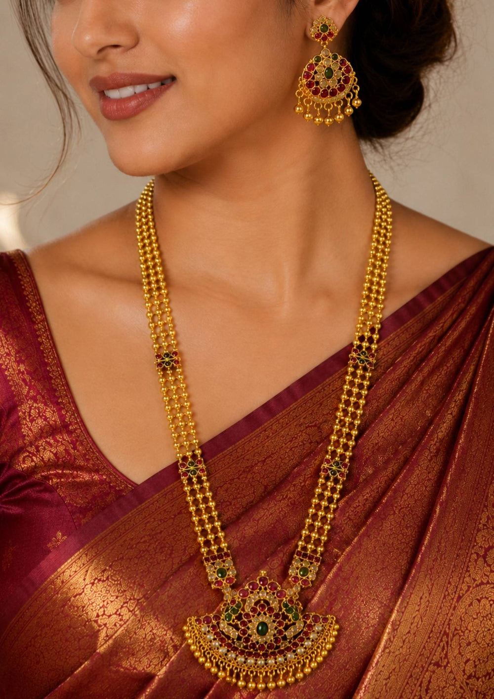 South Indian woman styling a jadau kundan gold plated long haram necklace set with matching earrings. The jewelry features layered bead chains, intricate kundan craftsmanship and traditional stone embellishments perfect for weddings and festive occasions.