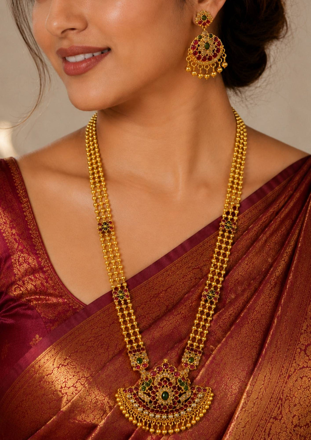 South Indian woman styling a jadau kundan gold plated long haram necklace set with matching earrings. The jewelry features layered bead chains, intricate kundan craftsmanship and traditional stone embellishments perfect for weddings and festive occasions.
