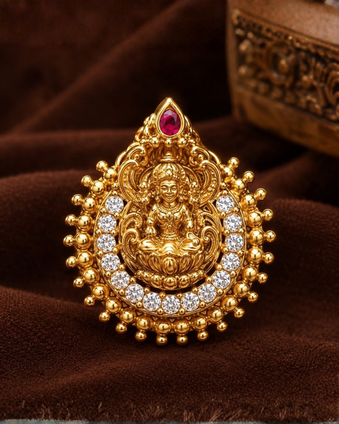 Close-up of South indian women ear wearing a Traditional Laxmi gold plated stud earrings . The circular ear studs feature a highly detailed embossed figure of Goddess Lakshmi sitting on a lotus in the center. The idol is semi-circled by shimmering white CZ American diamond stones, a beaded gold border, and a small red ruby stone at the very top tip. This temple jewelry piece provides an elegant ethnic look suitable for puja festivals, weddings, and traditional family occasions. 
